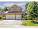 Tan two-story home featuring an attached two-car garage, neat landscaping, and a well-maintained lawn at 531 Saber Creek Dr, Monument, CO 80132