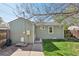 View of the side of the home with green siding, small deck, and grassy yard at 6819 Reno Dr, Arvada, CO 80002