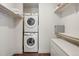 Compact laundry room with a stacked washer and dryer, built-in shelving, and ample storage space for convenience at 1898 S Bannock St # 510, Denver, CO 80223