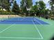 Bright and clean tennis court surrounded by mature trees and fencing at 7077 S Knolls Way, Centennial, CO 80122