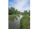 Scenic creek view bordered by lush greenery and a walking path, offering a tranquil natural setting at 10000 E Yale Ave # 58, Denver, CO 80231