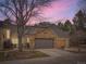 Charming home featuring a stone accent wall above the garage door and a beautiful sunset in the background at 10000 E Yale Ave # 58, Denver, CO 80231