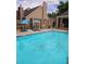 Community pool with clear water, lounge chairs, and tables with umbrellas at 10000 E Yale Ave # 58, Denver, CO 80231