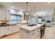 Bright, modern kitchen features an island cooktop, white cabinetry, and hardwood floors open to the living space at 2464 Ginny Way, Lafayette, CO 80026