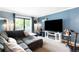 Light-filled living room features a sectional sofa, flatscreen TV, and sliding glass door to the balcony at 7780 W 38Th Ave # 203, Wheat Ridge, CO 80033