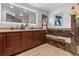 Bathroom with wooden cabinets, unique tile details, and a soaking tub for relaxation at 7845 Armadillo Trl, Evergreen, CO 80439