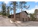 Brick home with a three-car garage and a side view featuring mature trees at 7845 Armadillo Trl, Evergreen, CO 80439