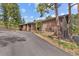 Brick home with an asphalt driveway is surrounded by mature trees and well-maintained landscaping at 7845 Armadillo Trl, Evergreen, CO 80439