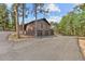 Spacious home with a three-car garage and ample parking, framed by mature trees and blue skies at 7845 Armadillo Trl, Evergreen, CO 80439