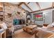 Living room featuring a stone fireplace, beamed ceilings, hardwood floors and comfortable seating at 7845 Armadillo Trl, Evergreen, CO 80439