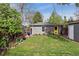 Green backyard featuring a shed with a yellow door, garden beds, and mature trees at 1343 Gay St, Longmont, CO 80501