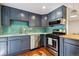 Charming kitchen featuring sleek stainless-steel appliances, stylish blue cabinets and a vibrant tile backsplash at 1343 Gay St, Longmont, CO 80501