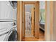 View of stacked laundry machines next to a bathroom and bedroom with hardwood flooring and wooden trim at 661 Tennyson St, Denver, CO 80204