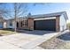 Single-Gathering home featuring a brick exterior, a black garage door, and mature trees at 1266 S Telluride St, Aurora, CO 80017