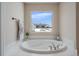 Bathroom with a large soaking tub and a window overlooking the backyard at 7295 Sunset Ave, Elizabeth, CO 80107