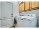 Well-lit laundry room boasting a stacked washer and dryer unit, upper cabinets, and a door at 17611 E 104Th Pl, Commerce City, CO 80022