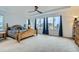 Spacious main bedroom featuring large windows, tray ceiling, ceiling fan and a wooden bed frame at 17611 E 104Th Pl, Commerce City, CO 80022
