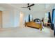 Bright main bedroom featuring large windows, tray ceiling, ceiling fan and a wooden bed frame at 17611 E 104Th Pl, Commerce City, CO 80022