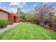 Green backyard featuring a well-maintained lawn, mature trees, and a red pergola covered patio at 11254 E Colorado Dr, Aurora, CO 80012