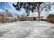 Expansive snowy backyard featuring a greenhouse, mature trees, and a covered patio, ideal for year-round enjoyment at 12843 W Jewell Cir, Lakewood, CO 80228