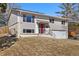 Split-level home featuring neutral siding, a red front door, attached garage, and a well-maintained front yard at 12843 W Jewell Cir, Lakewood, CO 80228