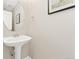 Stylish powder room features a pedestal sink, an oval mirror, and neutral paint at 10618 Clearview Ln, Highlands Ranch, CO 80126