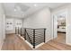 Upstairs hallway with hardwood floors, black railing, natural light, and a view into a bedroom at 10618 Clearview Ln, Highlands Ranch, CO 80126