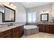 Elegant bathroom featuring dual vanities, a soaking tub with tile surround, and a large window for natural light at 10640 Winding Pine Pt, Highlands Ranch, CO 80126