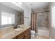 Stylish bathroom featuring granite counters, wood cabinets, and a shower with gray stone tiling at 10640 Winding Pine Pt, Highlands Ranch, CO 80126