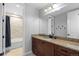 Bright bathroom featuring granite countertops, wood cabinets, and a shower with beige tiling at 10640 Winding Pine Pt, Highlands Ranch, CO 80126