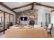 Inviting living room featuring a stone accent wall, wooden beams, fireplace and a large tan colored leather sofa at 10640 Winding Pine Pt, Highlands Ranch, CO 80126