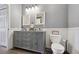 Bathroom with gray vanity, double sinks, and a toilet at 5255 Memphis St # 207, Denver, CO 80239