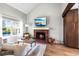 Comfortable living area featuring a brick fireplace with mounted television, hardwood floors, and natural light at 6960 S Knolls Way, Centennial, CO 80122
