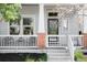 Close-up of a front porch with brick accents, white railing and seating at 5450 Uinta St, Denver, CO 80238