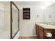 Bathroom with wood vanity and tub with patterned glass door and tile surround at 10102 W Ida Ave # 214, Littleton, CO 80127