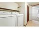 Bright laundry room features white appliances and functional shelving for convenient storage at 10102 W Ida Ave # 214, Littleton, CO 80127