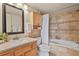 Bathroom featuring neutral tile, a bathtub with shower, wood vanity, and a framed mirror at 11085 Huron St # 1108, Northglenn, CO 80234