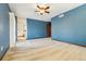Open bedroom with a ceiling fan and wood trim, leading to a bathroom and a wooden door at 6969 W Yale Ave # 81, Denver, CO 80227