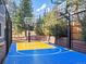 Bright blue and yellow basketball court with two hoops, surrounded by trees and black fencing at 4825 6Th St, Boulder, CO 80304