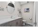 Modern bathroom featuring a floating vanity, round mirror, and gray flooring with a toilet at 1215 N Perry St, Denver, CO 80204