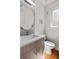 Bathroom featuring a circular mirror, modern vanity, toilet, and a window for natural light at 1215 N Perry St, Denver, CO 80204