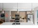 Bright kitchen with stainless steel appliances, wood cabinetry and a waterfall island with pendant lighting at 1215 N Perry St, Denver, CO 80204
