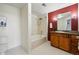 Bathroom with tile floors, a bathtub with shower, vanity, mirror and a red accent wall at 9481 E Mansfield Ave # 203, Aurora, CO 80014