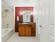 Bathroom featuring a bathtub with shower, vanity with mirror, and a vibrant red accent wall at 9481 E Mansfield Ave # 203, Aurora, CO 80014