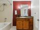 Bathroom with tile floors, bathtub with shower, wooden vanity and a red painted accent wall at 9481 E Mansfield Ave # 203, Aurora, CO 80014
