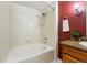 Bathroom with tiled tub and shower, a wooden vanity and a red accent wall at 9481 E Mansfield Ave # 203, Aurora, CO 80014