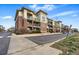 Street view of a three-story condo building with brick and siding, and green balconies at 9481 E Mansfield Ave # 203, Aurora, CO 80014