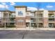 Three-story condo building with brick and siding, and green balconies in a suburban area at 9481 E Mansfield Ave # 203, Aurora, CO 80014