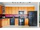 Well-lit kitchen with wood cabinetry, black appliances, and modern finishes at 9481 E Mansfield Ave # 203, Aurora, CO 80014