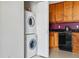 Kitchen area with stacked white washer and dryer next to wood cabinets at 9481 E Mansfield Ave # 203, Aurora, CO 80014